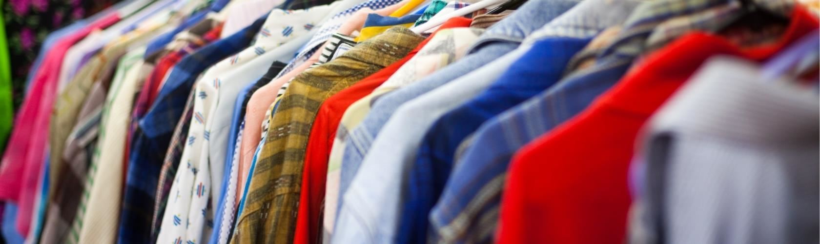 various shirts hanging on a clothes rack in a thrift store